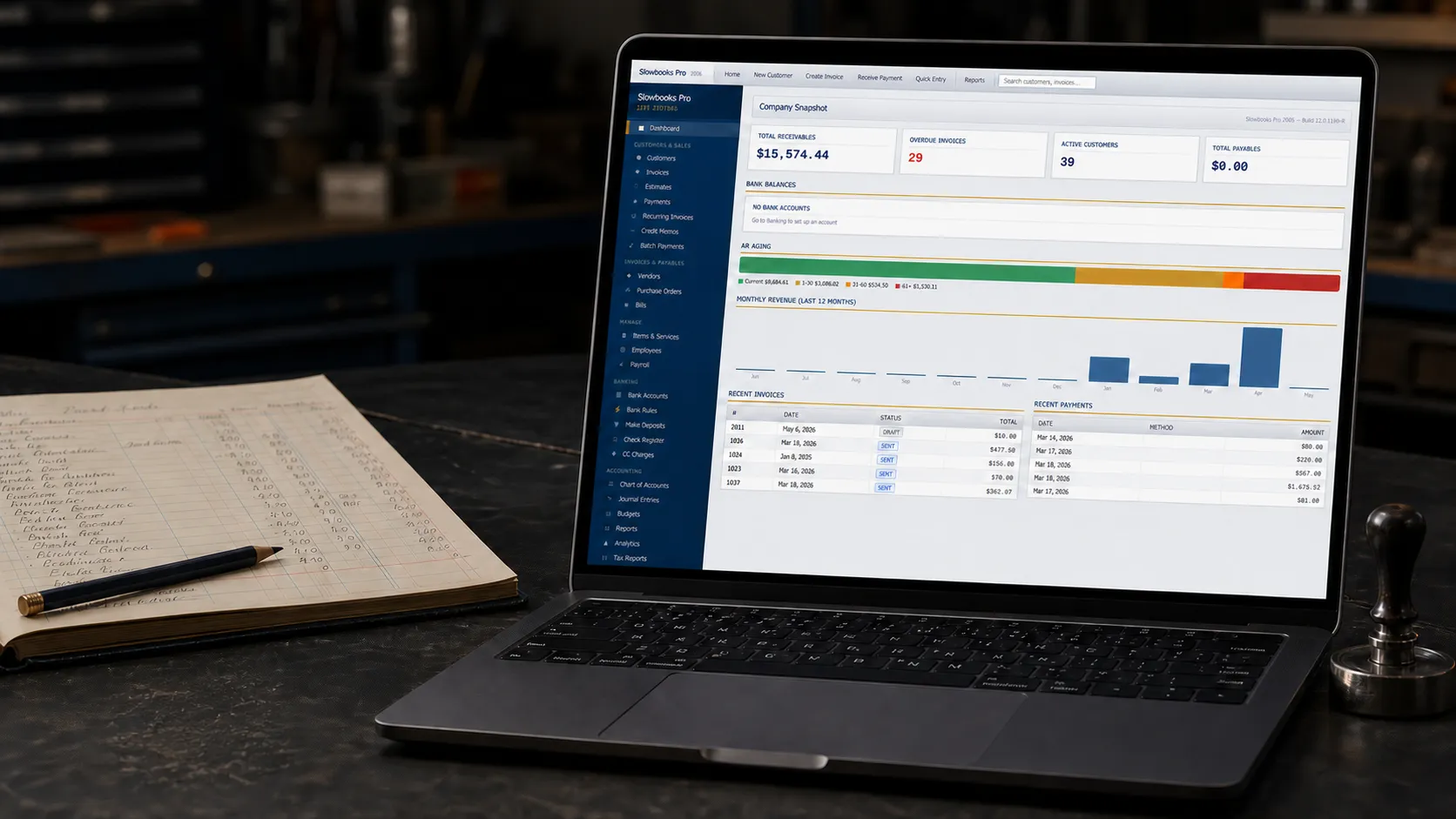 an editorial desk scene based on the real SlowBooks Pro interface, with the app running on a laptop beside a paper ledger and release stamp